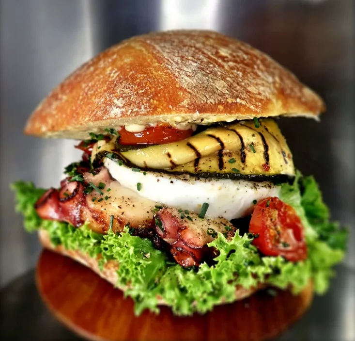 Burger POOLP : pain paillasse, poulpe mariné et snacké minute, courgette grillée, vinaigrette au thym frais et piment, tomate cerise confite, mozzarella di bufala, salade, mayo maison à l'ail confit