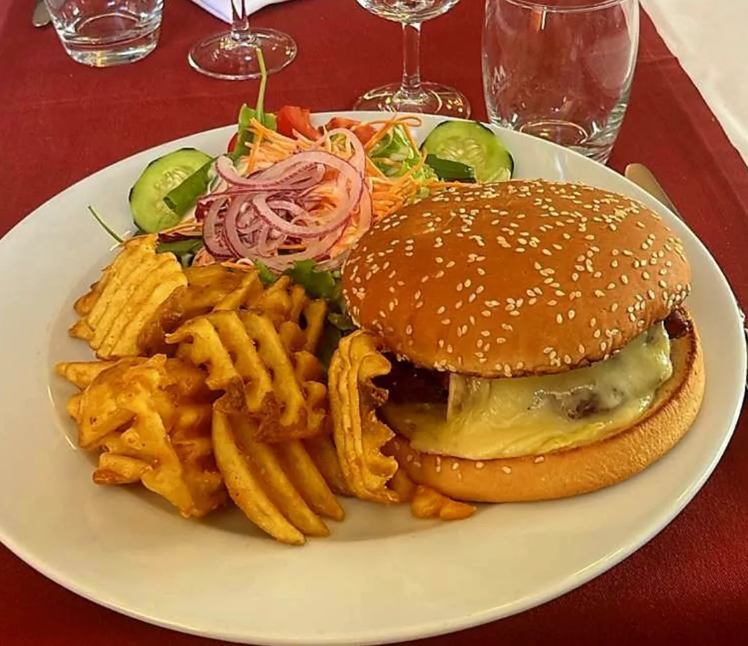 Hamburger de bœuf au fromage à raclette, pommes gaufrettes, salade et crudités