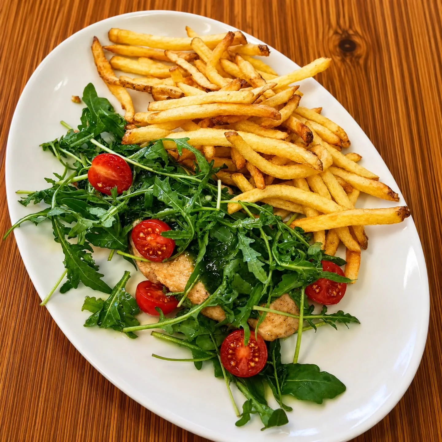 Tagliata de poulet, huile aux herbes, roquette, tomates cerises, frites fraîches