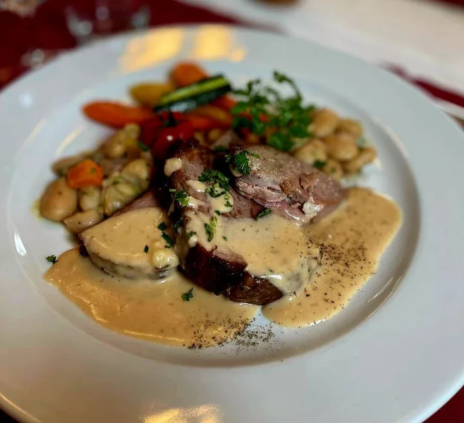 Gigot d'agneau rôti à la crème d'ail, flageolets mijotés, oignons et carottes