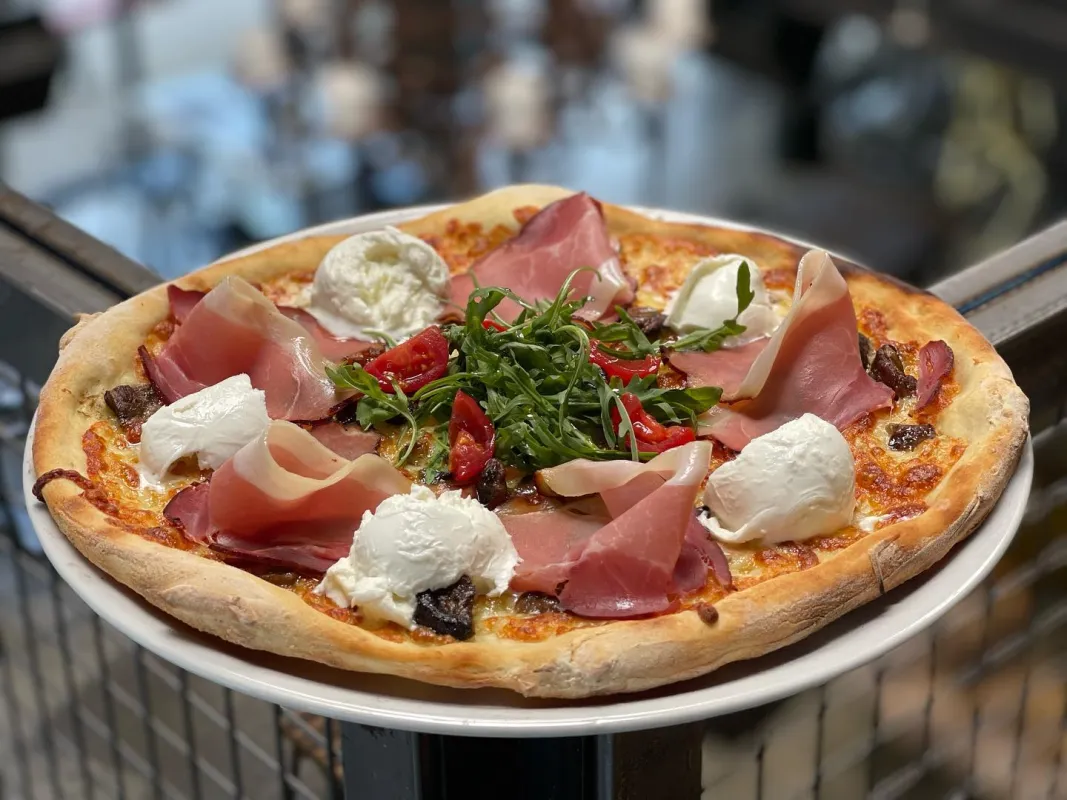 Pizza tomate, mozzarella, jambon de la Forêt-Noire, bolets, bufala, gorgonzola, tomates cerises, rucola.