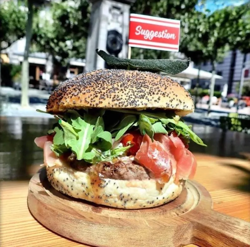 Burger Ratarocket : Bun boulanger, steak Beefore 150g, fromage burrata (I), tomates confites au miel et balsamique, pesto maison de sauge et basilic, jambon cru (I), salade roquette et balsamique