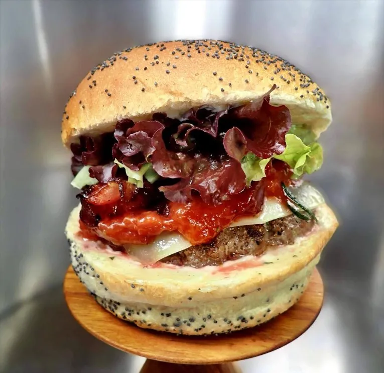 Burger le Pruno : Bun artisanal, steak Beefore ( bœuf/veau CH) 150g, raclette de Bagnes (VS), pruneaux de Fully (VS) mi-cuits au porto et romarin, bacon grillé (CH), salade et mayo maison au miel et romarin