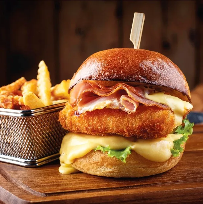 Cordon bleu burger, escalope de dinde panée, fromage à raclette, jambon cru, servi avec des frites maison