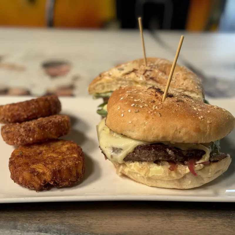 Burger Alsacien : Steak de boeuf, raclette, salade tomate et choucroute, aïoli pickles oignon rouge et mini roestie