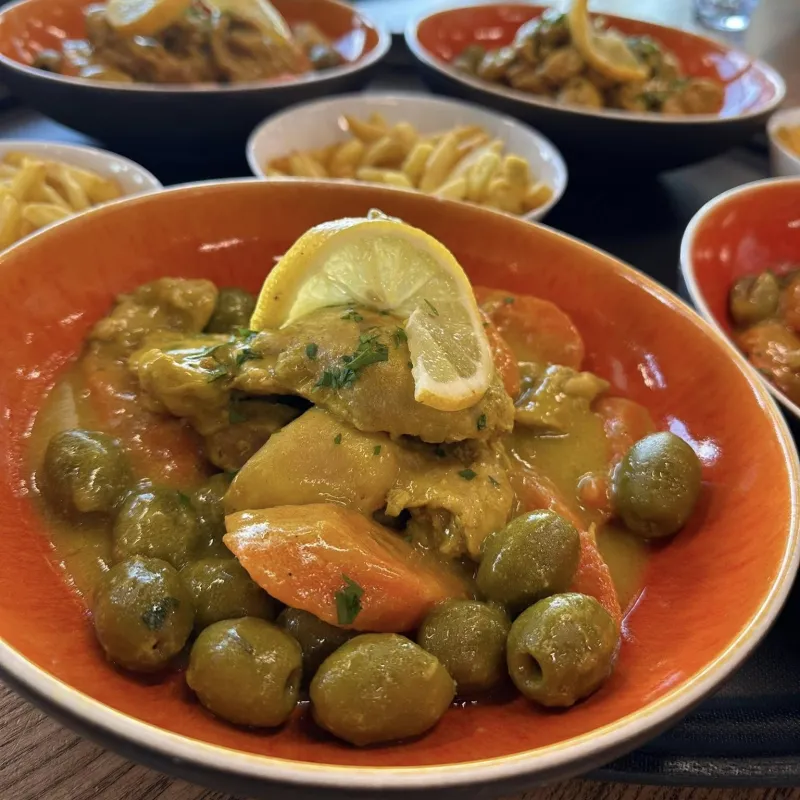 Tajine de poulet aux olives vertes et petits légumes, servi avec frites